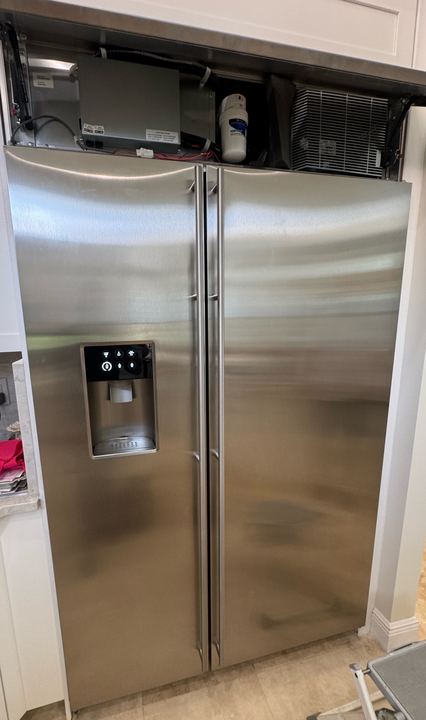 Stainless built-in side-by-side refrigerator with the top grille open to the machine compartment