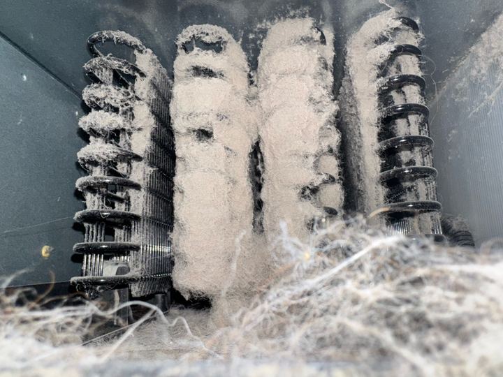 Condenser coil rows completely covered in lint and dust before cleaning