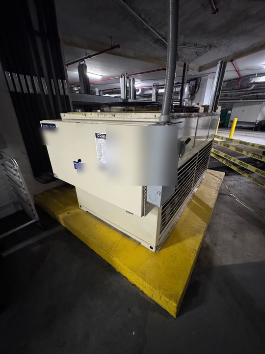 Cooltec multiplex condensing unit on a yellow equipment pad in a parking garage