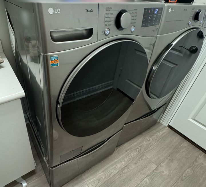 LG ThinQ front-load washer and dryer on pedestals in a laundry room