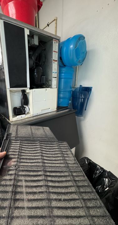 Commercial ice machine with a dust-clogged air filter being pulled out