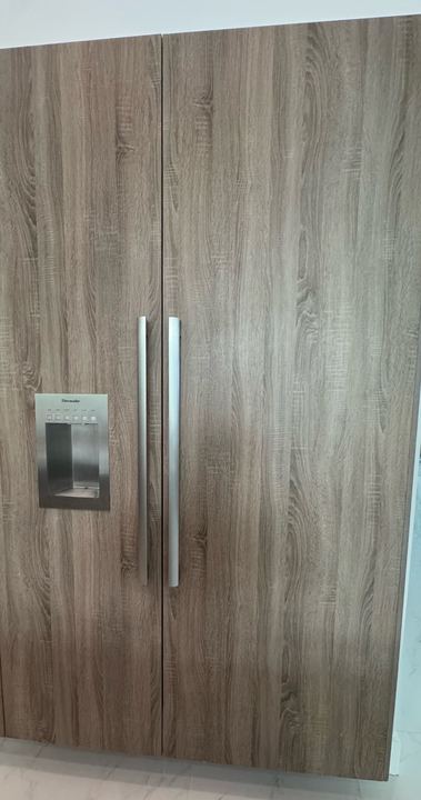 Panel-ready Thermador refrigerator and freezer columns with wood-grain doors and a built-in dispenser