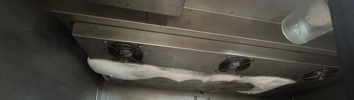 Evaporator fans inside a commercial reach-in covered with a band of ice
