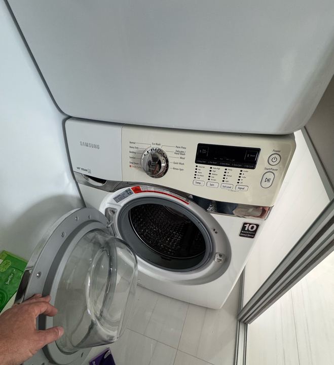 Technician's hand at the door of a Samsung front-load washer