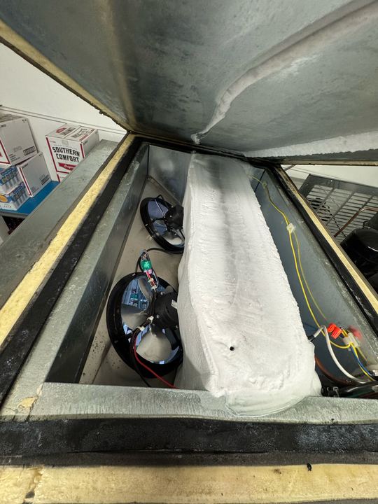 Walk-in cooler evaporator with the cover open and the coil encased in ice next to two fans